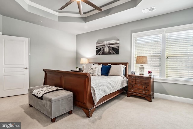 bedroom featuring light carpet, a tray ceiling, and ceiling fan