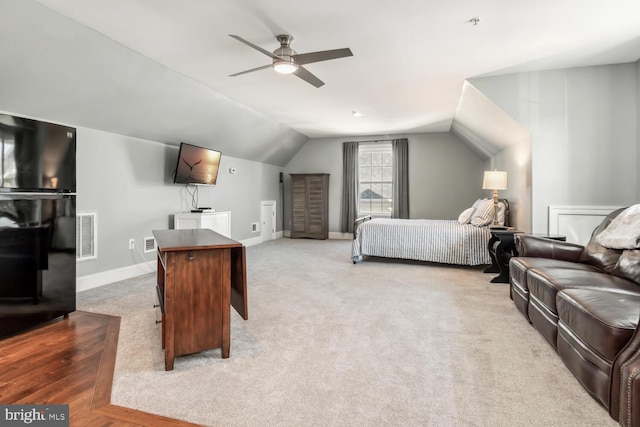 carpeted bedroom with ceiling fan, black refrigerator, and vaulted ceiling