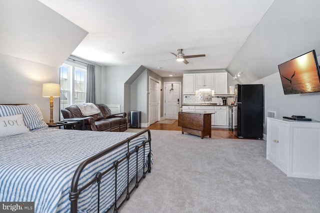 bedroom with ceiling fan, black fridge, light colored carpet, and lofted ceiling