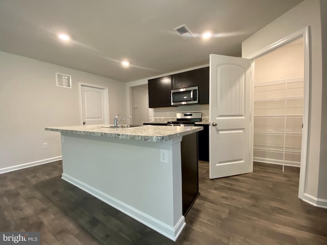 kitchen featuring dark hardwood / wood-style flooring, stainless steel appliances, a center island with sink, and sink