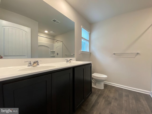 bathroom with toilet, hardwood / wood-style floors, vanity, and walk in shower