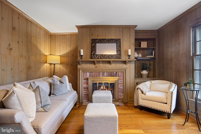 living room with a fireplace, light wood-type flooring, and wood walls