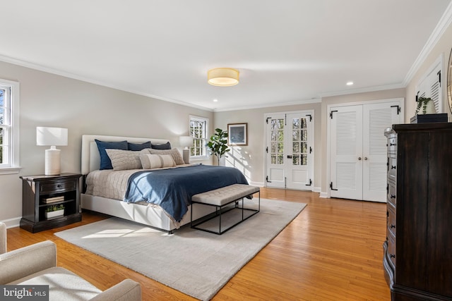 bedroom featuring multiple windows, crown molding, and light wood-type flooring