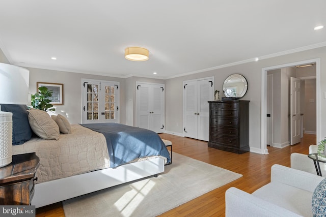 bedroom with wood-type flooring, ornamental molding, and two closets