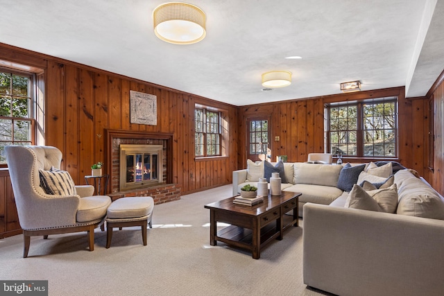 carpeted living room featuring plenty of natural light, wooden walls, and a fireplace