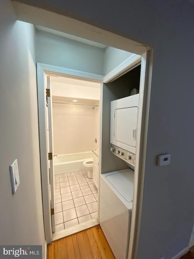 clothes washing area with stacked washing maching and dryer and light hardwood / wood-style floors