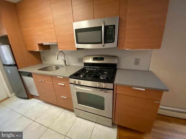 kitchen featuring sink, light tile patterned floors, stainless steel appliances, and a baseboard heating unit