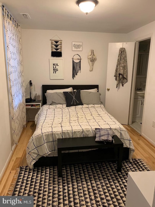 bedroom with ensuite bathroom and light wood-type flooring