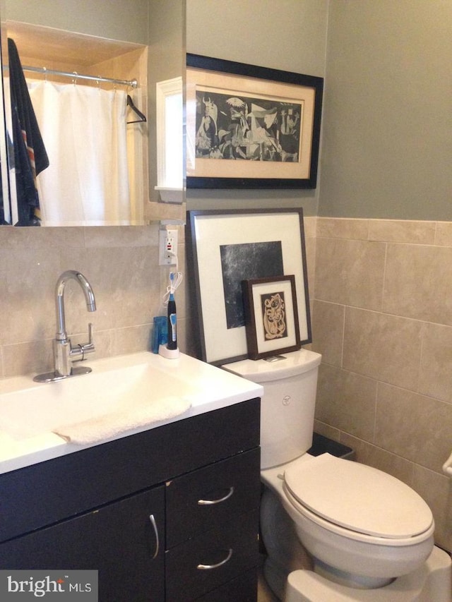 bathroom with vanity, toilet, tile walls, and walk in shower