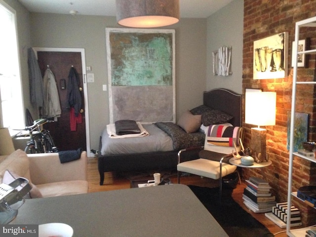 bedroom with wood-type flooring and brick wall