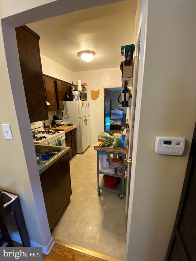 kitchen featuring dark brown cabinets and white appliances