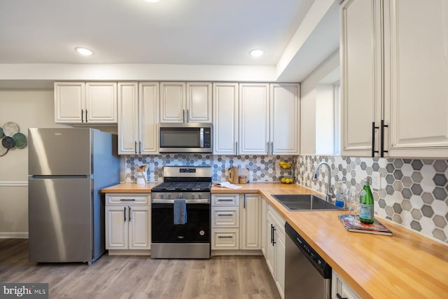 kitchen featuring sink, appliances with stainless steel finishes, light wood-type flooring, and wood counters