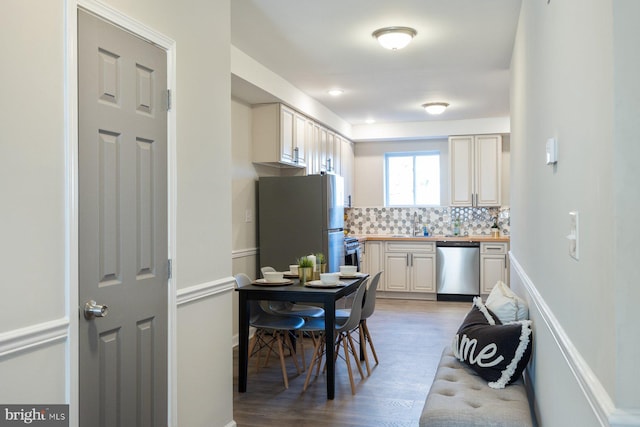 kitchen with sink, wood-type flooring, stainless steel appliances, and tasteful backsplash