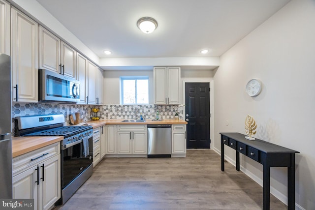 kitchen featuring backsplash, wooden counters, stainless steel appliances, and light hardwood / wood-style flooring