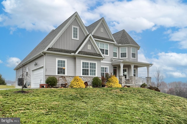 craftsman house featuring a garage, a porch, and a front lawn