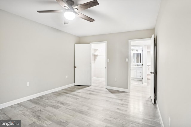 unfurnished bedroom with ceiling fan, sink, light hardwood / wood-style flooring, a spacious closet, and a closet