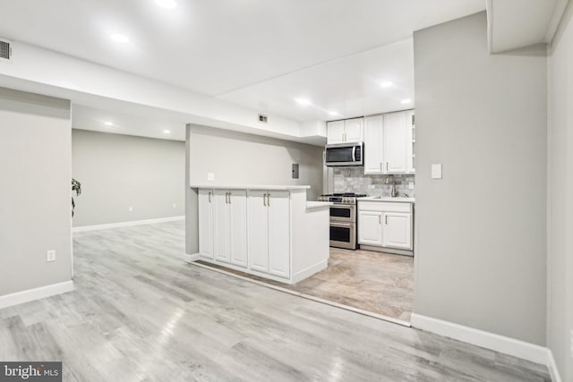 kitchen featuring decorative backsplash, stainless steel appliances, sink, light hardwood / wood-style flooring, and white cabinetry