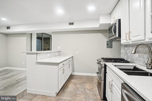 kitchen with white cabinetry, light stone countertops, light hardwood / wood-style flooring, backsplash, and appliances with stainless steel finishes