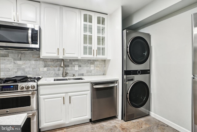 kitchen with white cabinetry, sink, tasteful backsplash, stacked washer / drying machine, and appliances with stainless steel finishes