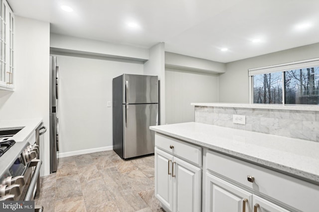 kitchen featuring tasteful backsplash, white cabinetry, stainless steel appliances, and light stone counters