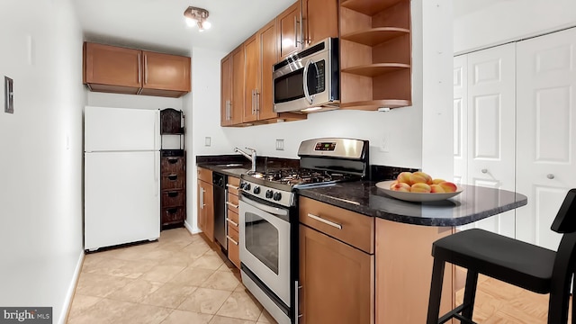 kitchen with a breakfast bar, sink, light tile patterned flooring, kitchen peninsula, and stainless steel appliances