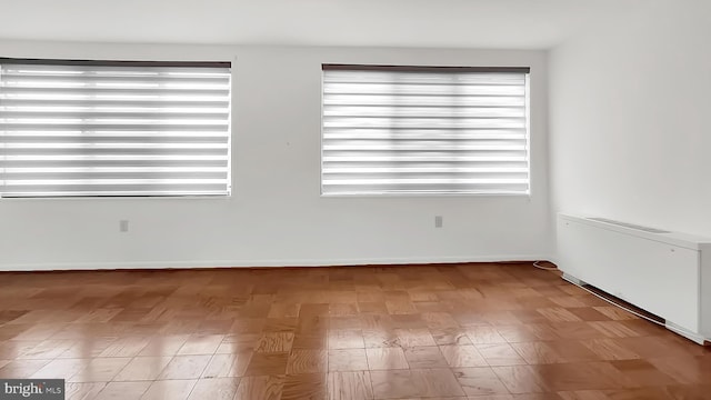 spare room featuring radiator, a wealth of natural light, and light hardwood / wood-style flooring