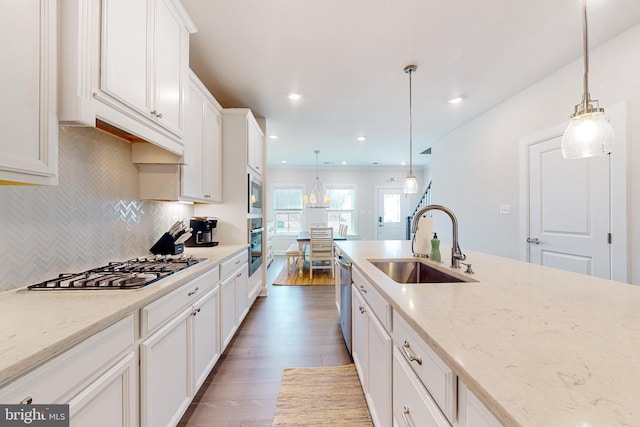 kitchen featuring white cabinets, appliances with stainless steel finishes, hanging light fixtures, and sink