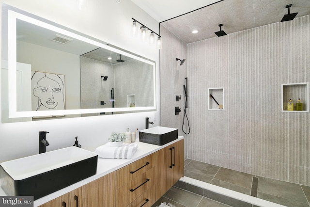 bathroom with tiled shower, vanity, and tile patterned floors