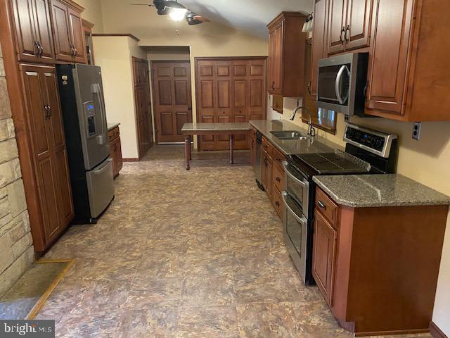 kitchen with dark stone counters, sink, and stainless steel appliances