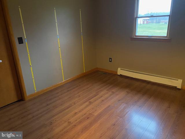 spare room featuring a baseboard radiator and hardwood / wood-style flooring