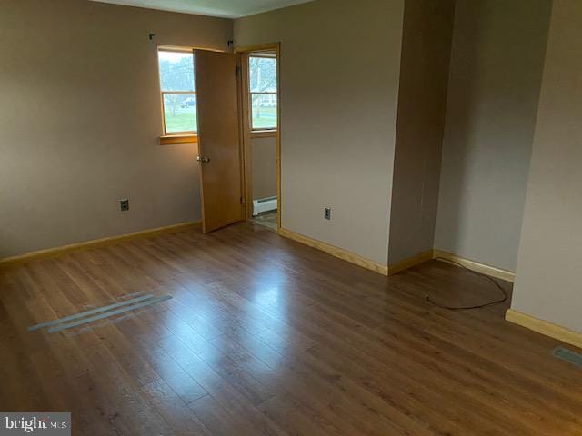 empty room featuring wood-type flooring and a baseboard radiator