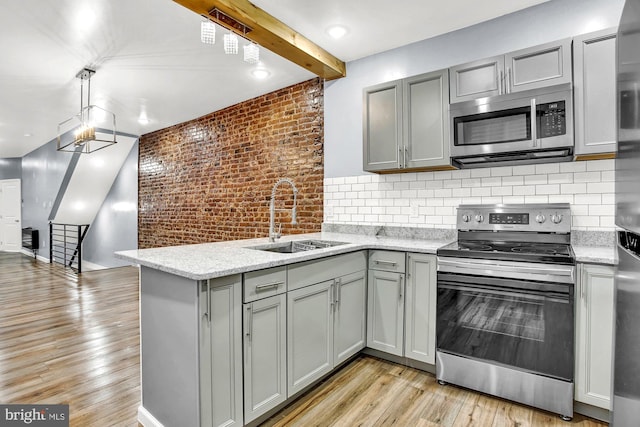 kitchen with brick wall, appliances with stainless steel finishes, light hardwood / wood-style floors, and sink