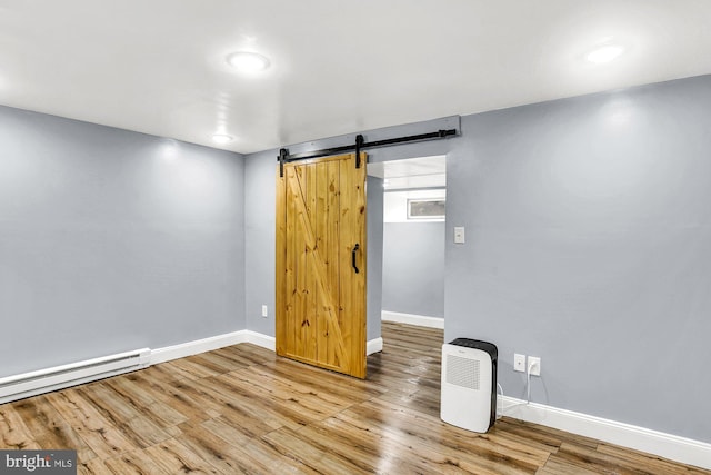 spare room featuring hardwood / wood-style floors, a barn door, and baseboard heating