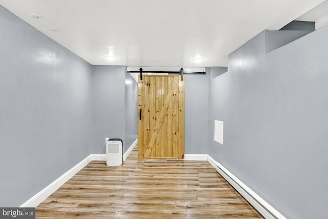 basement with a barn door and light hardwood / wood-style floors