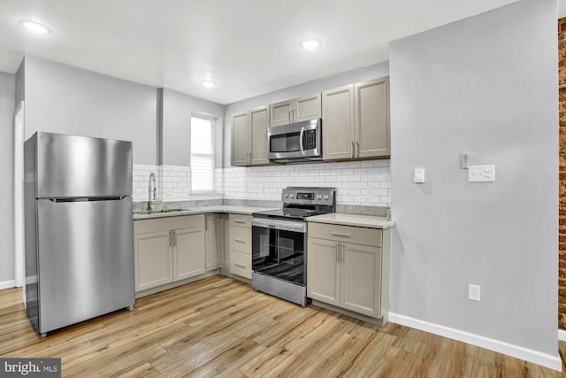 kitchen featuring appliances with stainless steel finishes, light hardwood / wood-style floors, gray cabinetry, and sink