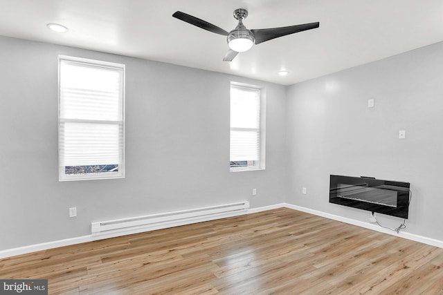 unfurnished living room with baseboard heating, ceiling fan, a healthy amount of sunlight, and light hardwood / wood-style floors