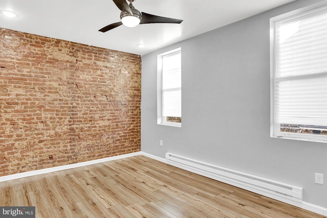 spare room with ceiling fan, light hardwood / wood-style flooring, a baseboard radiator, and brick wall