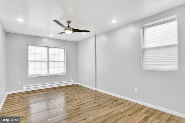 spare room featuring a baseboard radiator, light hardwood / wood-style flooring, and ceiling fan