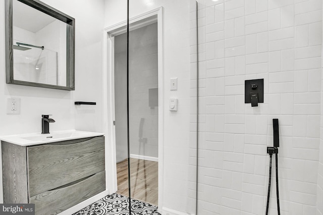 bathroom featuring vanity, a tile shower, and wood-type flooring