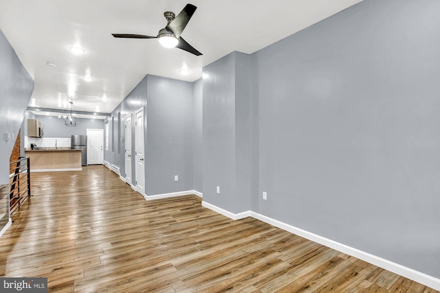 empty room featuring ceiling fan with notable chandelier, hardwood / wood-style flooring, and a baseboard radiator