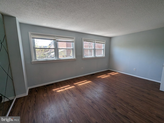 empty room with a textured ceiling and dark hardwood / wood-style floors