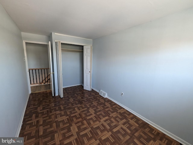 unfurnished bedroom with dark parquet flooring