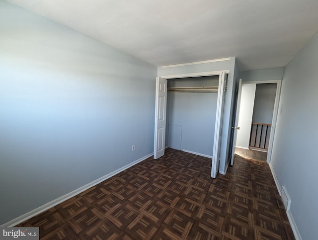 unfurnished bedroom featuring dark parquet flooring and a closet