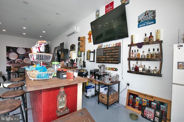 bar with white refrigerator, an AC wall unit, and concrete flooring