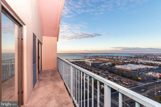 balcony at dusk featuring a water view