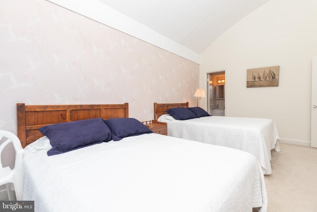 carpeted bedroom featuring ensuite bath and vaulted ceiling