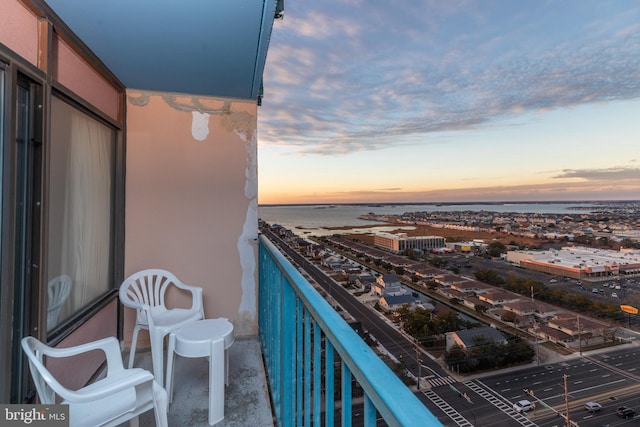 balcony at dusk featuring a water view