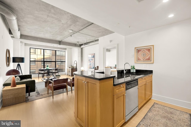 kitchen featuring light wood finished floors, a peninsula, a sink, dishwasher, and dark countertops