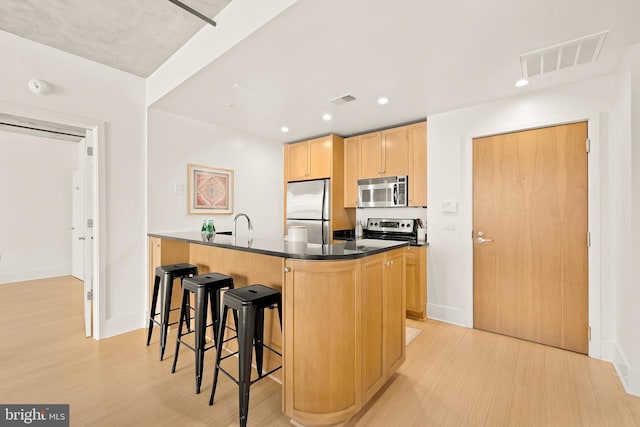 kitchen with dark countertops, visible vents, light brown cabinetry, and stainless steel appliances