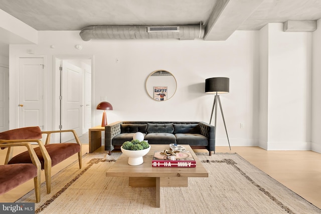 living room featuring visible vents, baseboards, and wood finished floors